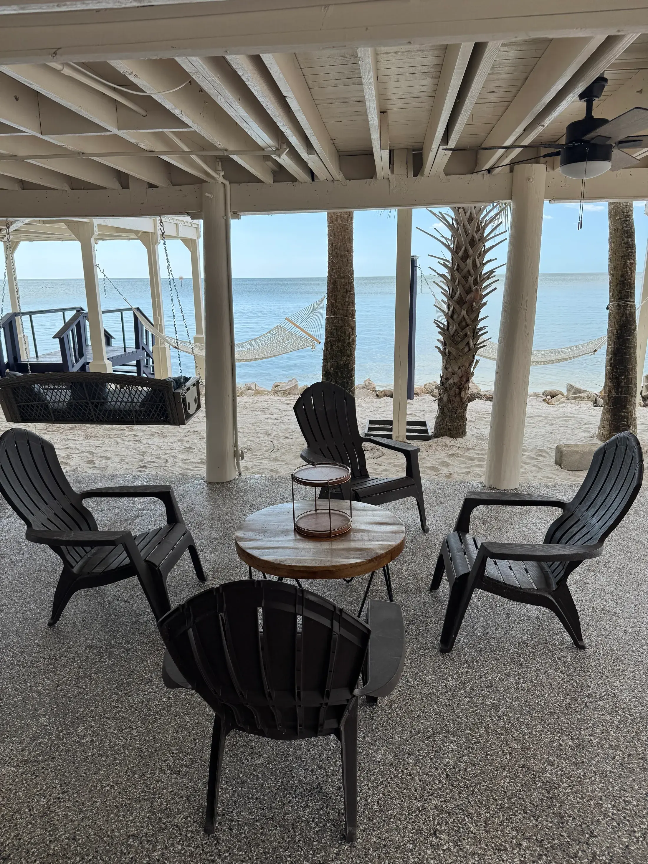 Covered lower-level seating area looking out toward the private beach and Gulf.