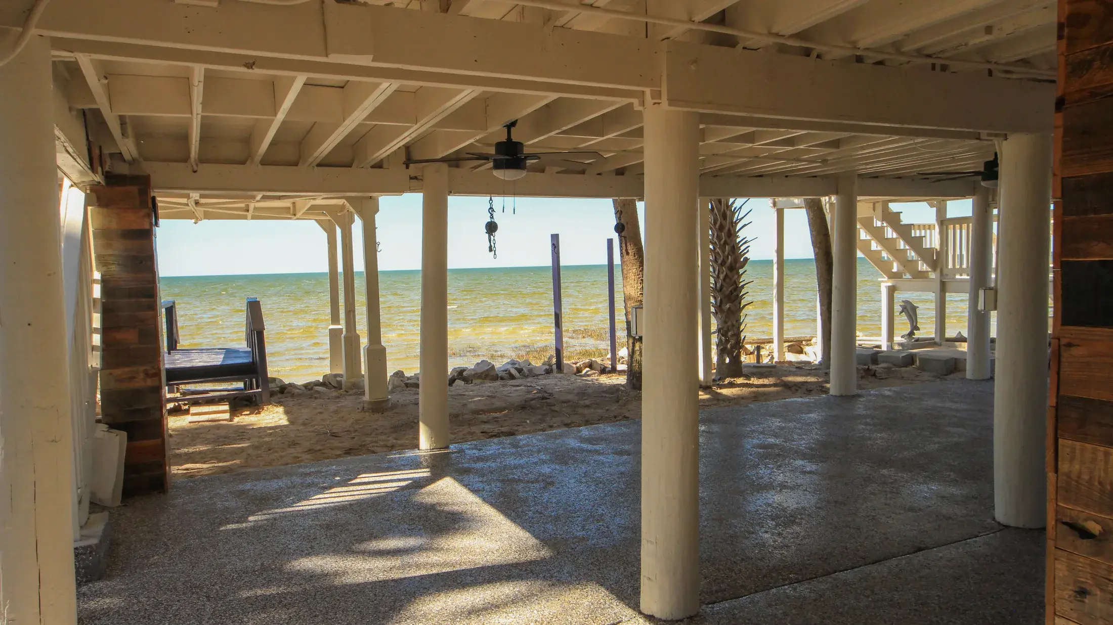 Large covered ground-level area under the home with Gulf views beyond.