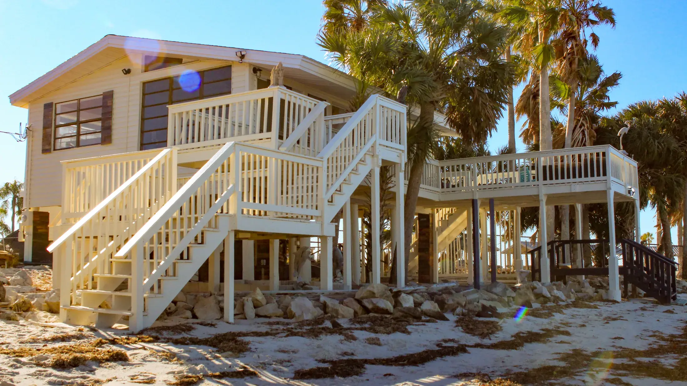 Front exterior of the Gulf-front stilt house with stairs leading up to the main entry.