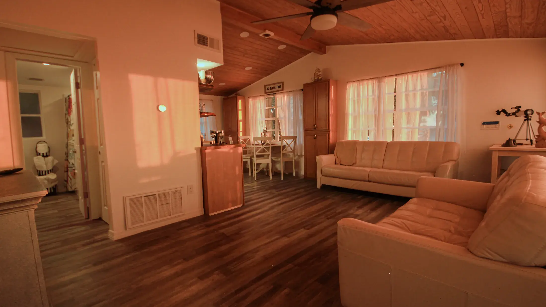Open living and dining view showing couches, dining table, and bright coastal interior.